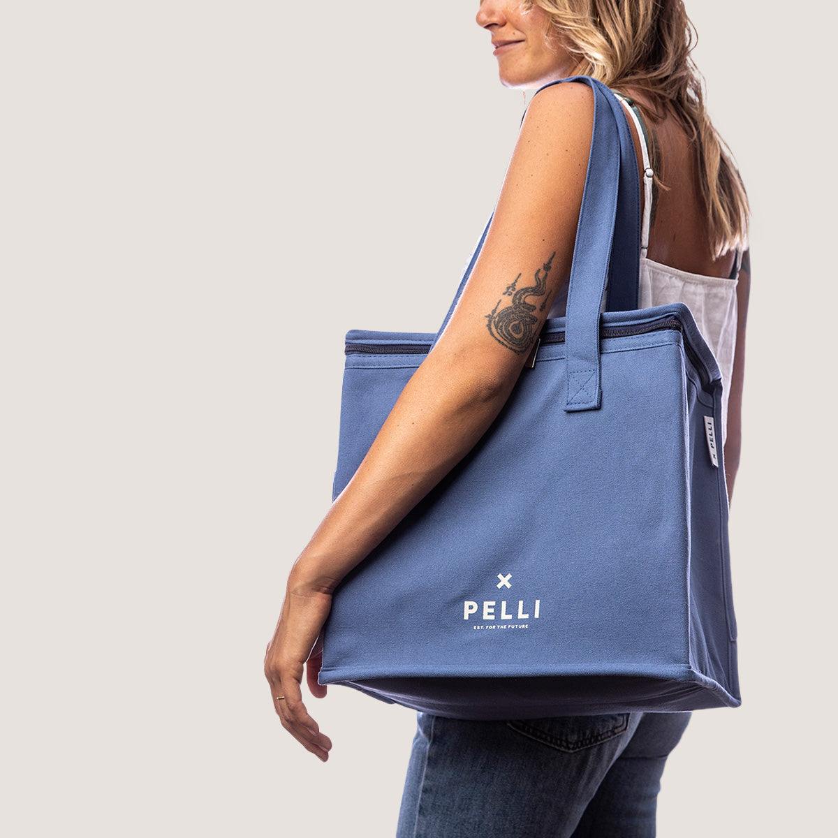 Load image into Gallery viewer, A woman carrying a canvas medium cooler bag in ocean blue on her shoulder
