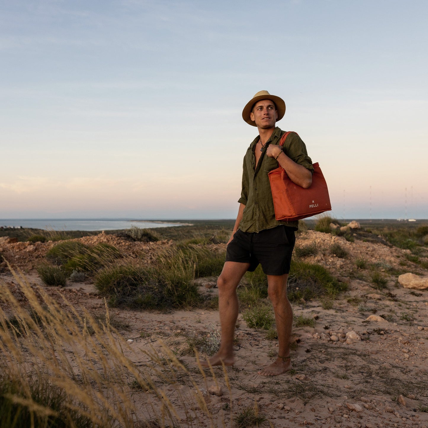 Load image into Gallery viewer, A man standing on a field carrying a medium cooler bag in clay on his shoulder
